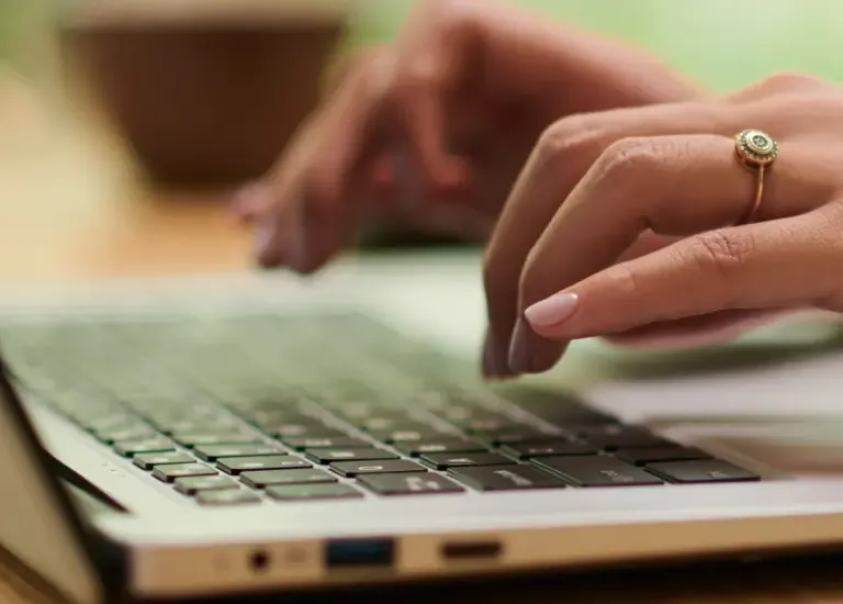 a woman using a laptop computer on a wooden table