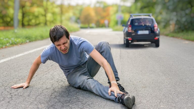 Injured man on road in front of a car