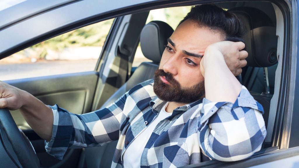 Young man sitting inside the car is very sad