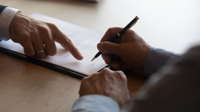 Hands of lawyer pointing at paper where to sign